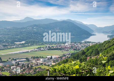 Lago di Lugano, Schweiz. Malerische Luftaufnahme der Stadt von Agno, Lago di Lugano, Lugano Flughafen an einem schönen Sommertag Stockfoto