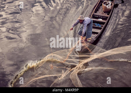 Fischer, die mit Fischen net Fisch bei TaugThaMan See unterhalb U-Bein Brücke in Amarapura, in der Nähe von Mandalay, Myanmar, Birma zu fangen. Stockfoto