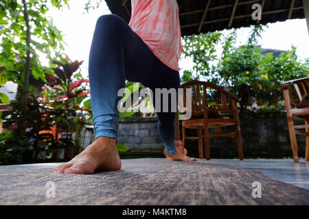 Junge Frau Yoga Asana Virabhadrasana Warrior Pose auf der Terrasse während der Ferien. Stockfoto