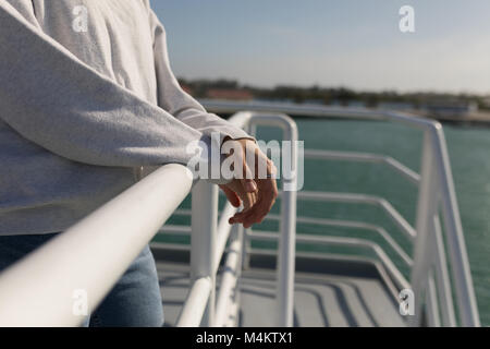 Frau, die in der Nähe von Geländer von Kreuzfahrtschiff Stockfoto