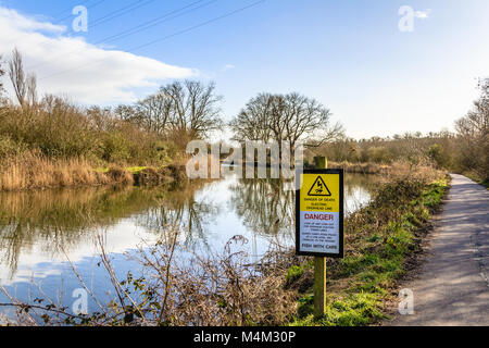 Warnschild neben dem Fluss exe informiert Freizeitfischer über die Gefahren von Oberleitungen. Stockfoto