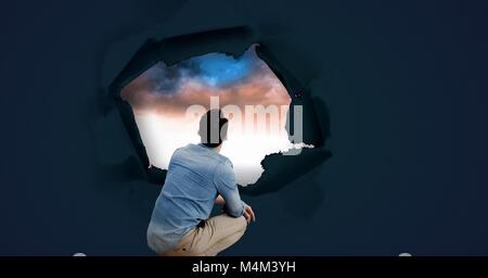 Mann durch surreale Papier Loch am Himmel suchen Stockfoto