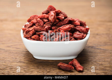 Goji Beeren in Weiß Schüssel auf Holz- Hintergrund Stockfoto