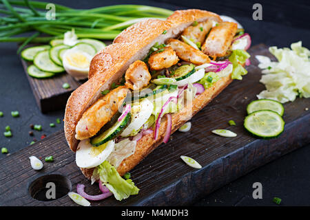 Baguette Sandwich mit Fisch, Ei, eingelegte Zwiebeln und Salatblätter. Stockfoto