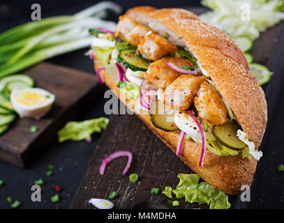 Baguette Sandwich mit Fisch, Ei, eingelegte Zwiebeln und Salatblätter. Stockfoto