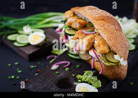 Baguette Sandwich mit Fisch, Ei, eingelegte Zwiebeln und Salatblätter. Stockfoto