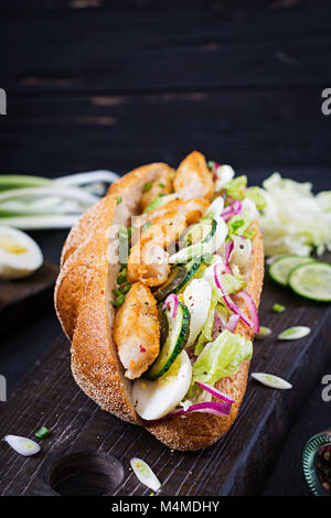 Baguette Sandwich mit Fisch, Ei, eingelegte Zwiebeln und Salatblätter. Stockfoto