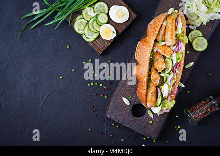 Baguette Sandwich mit Fisch, Ei, eingelegte Zwiebeln und Salatblätter. Ansicht von oben Stockfoto