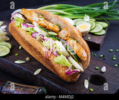 Baguette Sandwich mit Fisch, Ei, eingelegte Zwiebeln und Salatblätter. Stockfoto