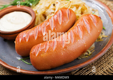 Platte mit Wurst und Sauerkraut auf hölzernen Tisch. Traditionelle Oktoberfest Menü Stockfoto