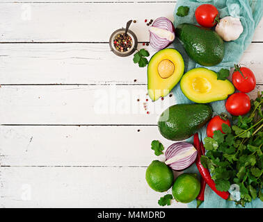 Guacamole sauce Zutaten - Avocado, Tomate, Zwiebel, Pfeffer, Chili, Knoblauch, Koriander, Limette auf weißem Hintergrund. Ansicht von oben Stockfoto