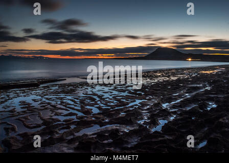 Sonnenuntergang am Strand mit der Scheinwerfer eines Autos Beleuchtung eines weit weg, die Insel La Graciosa, Kanarische Inseln, Spanien Stockfoto