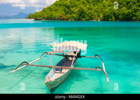 Traditionelle Boot schwimmend auf dem transparent blau getönten Lagune der remote Togean (oder) Togian Inseln, Sulawesi, Indonesien, Reiseziel. Stockfoto