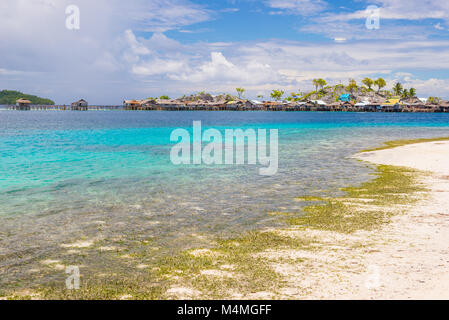 Tropischen Strand mit türkisblauem Wasser und grünen Dschungel in der entfernten Togean (oder) Togian Inseln, Sulawesi, Indonesien. Inselchen und Fischer Stockfoto