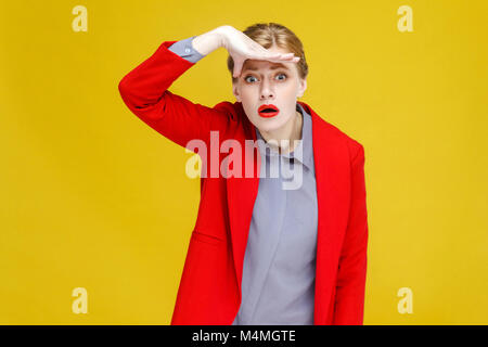 Roter Kopf Frau im roten Anzug weit weit weg. Studio shot, auf gelbem Hintergrund Stockfoto