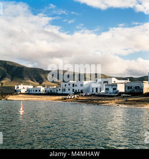 Spielzeug Segelboot auf das Meer, während die Dorfbewohner ziehen ein Fischerboot bis zum Strand in einem kleinen Dorf, Lanzarote, Kanarische Inseln, Spanien, Archivierung Foto Januar 1988 Stockfoto