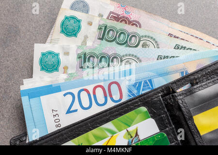 Neue Russische Banknoten im Wert von 1000, 2000 und 5000 Rubel und Kreditkarten in einem schwarzen Leder Geldbörse Nahaufnahme, Ansicht von oben Stockfoto