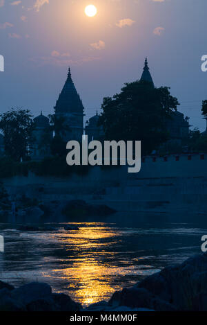 Orchha Stadtbild aus dem Fluss bei Sonnenuntergang, Tempel Silhouette. Auch buchstabiertes Orcha, berühmte Reiseziel in Madhya Pradesh, Indien. Stockfoto