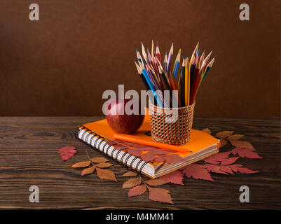 Bunte Bleistifte, Apple und trockenen Herbst Blätter auf Holztisch. Stockfoto