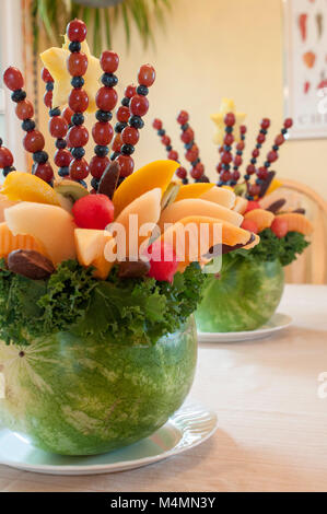 Zwei Anordnungen von geschnitten und aufgespießt Obst in Schalen von Wassermelone geschnitzt Stockfoto