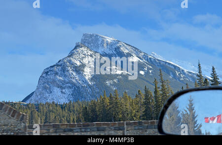 Blick auf die Rockies und hinterlässt eine Stadt mit der kanadischen Flagge im Spiegel Stockfoto