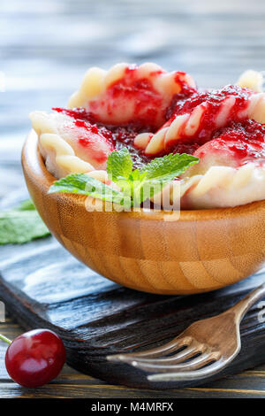 Hausgemachte Knödel mit Kirschen in eine hölzerne Schüssel. Stockfoto