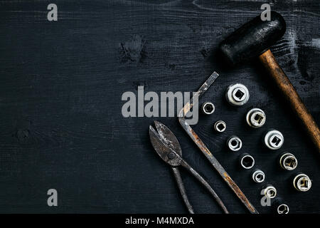 Kopieren von Tools auf einem schwarzen Holz- Oberfläche. Zange, Schraubenschlüssel, Zangen, Schraubendreher, Hammer. Ansicht von oben. Immer noch leben. Flach Stockfoto