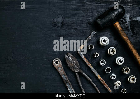 Kopieren von Tools auf einem schwarzen Holz- Oberfläche. Zange, Schraubenschlüssel, Zangen, Schraubendreher, Hammer. Ansicht von oben. Immer noch leben. Flach Stockfoto