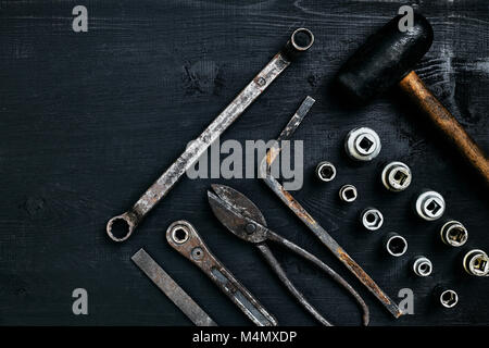 Kopieren von Tools auf einem schwarzen Holz- Oberfläche. Zange, Schraubenschlüssel, Zangen, Schraubendreher, Hammer. Ansicht von oben. Immer noch leben. Flach Stockfoto