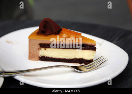 Ein Stück Schokolade orange Mousse Torte auf dem Teller mit Gabel im Cafe Stockfoto