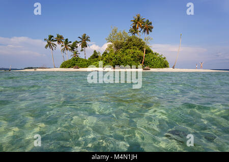 Frau und Junge stehend auf einem Sandstrand heben die Hände auf einer kleinen tropischen Insel am Horizont in wunderschönen tropischen türkis blauen Wasser. Stockfoto