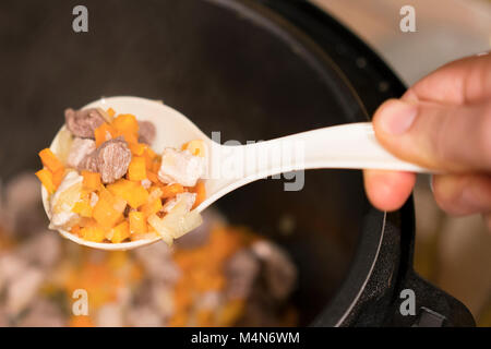 Gekochtes Fleisch mit Gemüse in ein warmes Weiß Löffel auf einen Hintergrund. Stockfoto