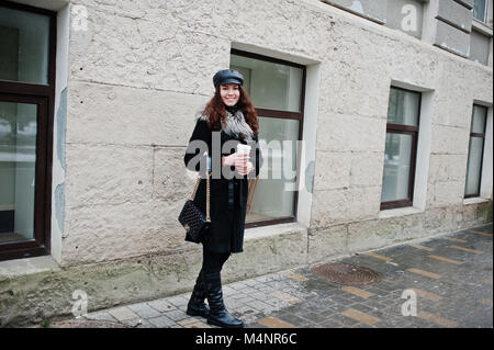 Curly mexikanische Mädchen in Leder und Plastik Tasse Kaffee zur Hand gehen an Straßen der Stadt. Stockfoto