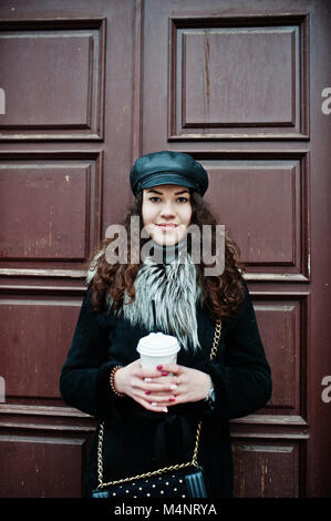 Curly mexikanische Mädchen in Leder und Plastik Tasse Kaffee zur Hand gehen an Straßen der Stadt. Stockfoto