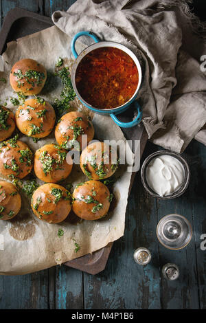 Pan der traditionellen Rote-Bete-Suppe Borschtsch mit saurer Sahne und frischem Koriander serviert mit Knoblauch Brötchen pampushki, Glas Wodka, textilen Leinen über Stockfoto