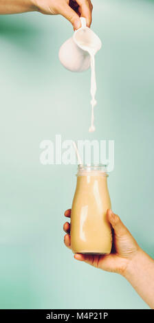 Womans Hand smoothie Schütteln gegen helle Wand. Gießen Milch in Smoothie. Trinken gesunde Smoothie Konzept Stockfoto