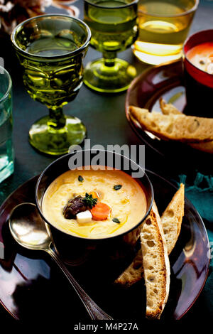 Wein Gemüse Bisque serviert mit Brot und Wein. Auf dunkelblauem Hintergrund fotografiert. Stockfoto