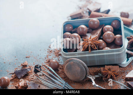 Rustikale Metall mit Pralinen und zerbrochenes Schokolade mit Gewürzen, Anis, Zimt und Kakao auf dem Marmor Hintergrund. Süße Konzept. Stockfoto