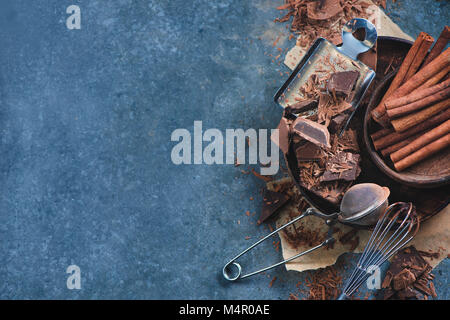 Küche auf einem Marmor Küchentisch. Schneebesen und Kakao Sieb mit Stücken von gebrochene Schokolade, Gewürzen, Anis, Zimt und Kakao auf einen Stein Stockfoto