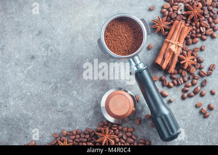Kaffee mit kopieren. Portafilter mit gemahlenen Kaffee, Sabotage, Zimt und Bohnen auf einem Marmor Hintergrund. Stockfoto