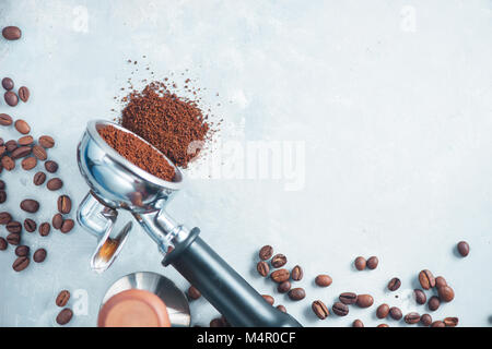 Portafilter mit verstreuten gemahlenen Kaffee. Geräte, die für das Aufbrühen von Kaffee auf einem hellen Hintergrund mit kopieren. Stockfoto