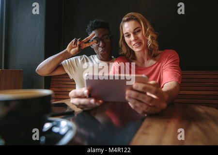 Lächelndes Paar ein selfie über Handy an einem Tisch sitzen. Mann und Frau teilen glückliche Momente im Coffeeshop. Stockfoto