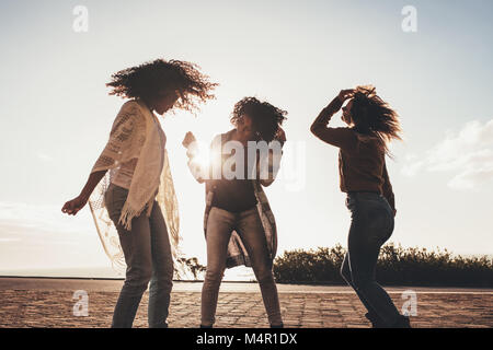 Weibliche Freunde tanzen und Spaß entlang der Straße keine einen sonnigen Tag. Drei junge Frauen genießen Sie auf Ihrer Reise. Freundinnen in den Urlaub genießen. Stockfoto