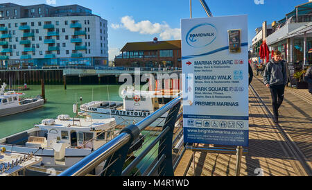 Brighton Marina Village, ein Hinweisschild auf dem Board Walk mit luxuriösen Apartments im Hintergrund ein sehr beliebter Platz in Brighton zu gehen Stockfoto