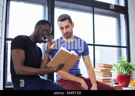 Lächelnd afrikanische amerikanische Mann mit lässigen Freund ein Buch lesen. Stockfoto