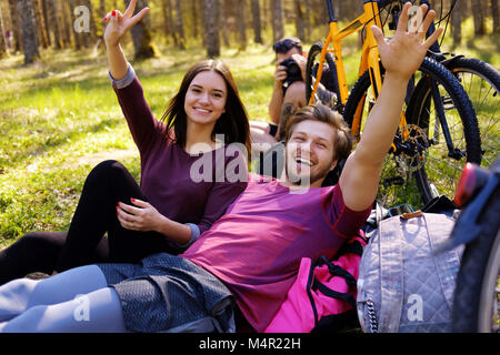 Eine männliche und zwei weibliche Entspannen in einem Park nach dem Reiten mit Fahrrädern. Stockfoto