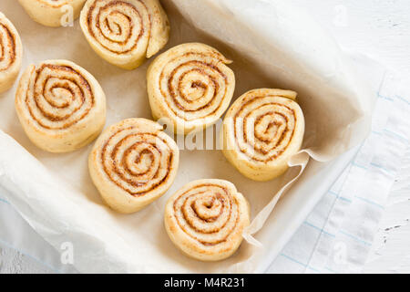 Zimtschnecken oder cinnabon, selbstgemachtes Rezept Rohteig Vorbereitung süß traditionell Dessert Gebäck Gebäck essen auf backblech. Stockfoto