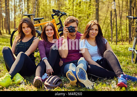 Groupe von Menschen entspannend nach der Fahrt mit dem Fahrrad in den Wald. Ein Mann mit digitalen Kompakt Foto Kamera. Stockfoto