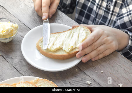 Männliche Hände Verbreitung Butter auf geröstetem Brot beim Frühstück am Morgen. Frühstück zu Hause mit Brot, Butter und Kaffee. Stockfoto