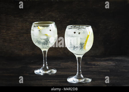 Alkohol trinken (Gin Tonic Cocktail) mit Zitrone und Eis auf rustikalen schwarzen Holztisch, Kopieren, Ansicht von oben. Iced Drink mit Zitrone. Stockfoto